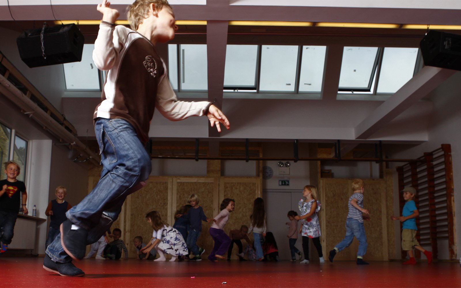 Young children playing in the school gym with roof skylights and roof ventilation